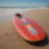 A vibrant soft longboard surfboard displayed on the beach