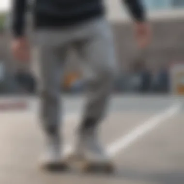 Individual performing a trick in grey sweatpants with elastic ankles at a skate park